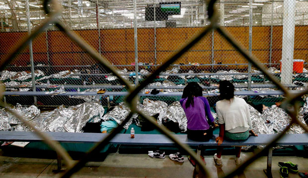 Two young girls sit in their holding area where hundreds of mostly Central American immigrant children are being processed and held at the U.S. Customs and Border Protection Nogales Placement Center on June 18, 2014, in Nogales, Arizona. (AP/Ross D. Franklin)