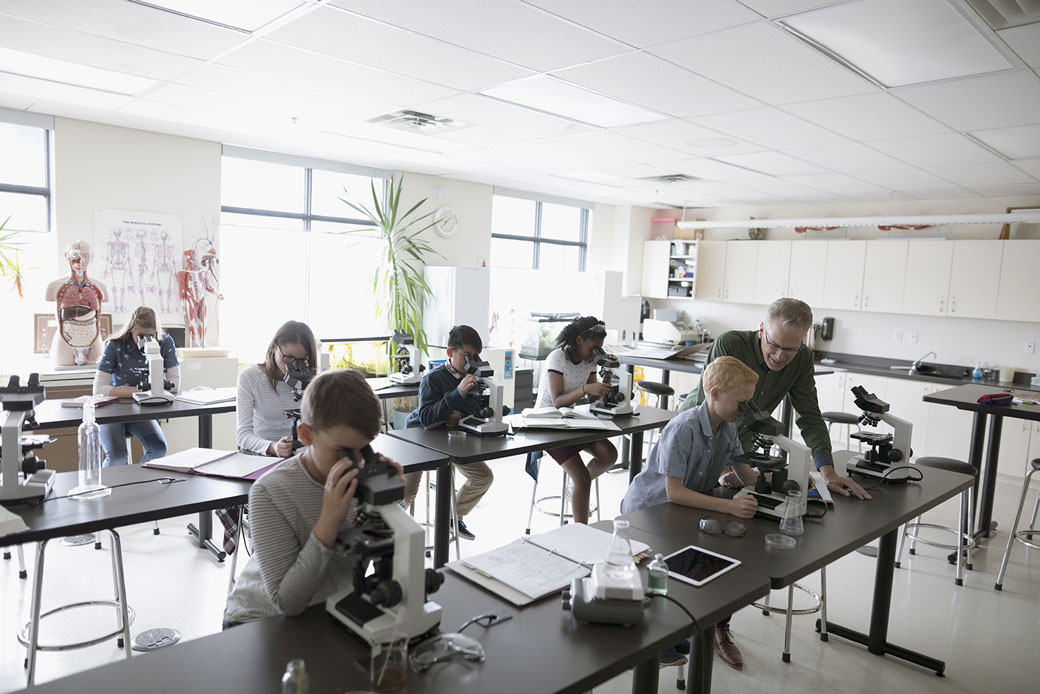 Middle school students use microscopes to conduct a scientific experiment. (Getty/Hero Images)