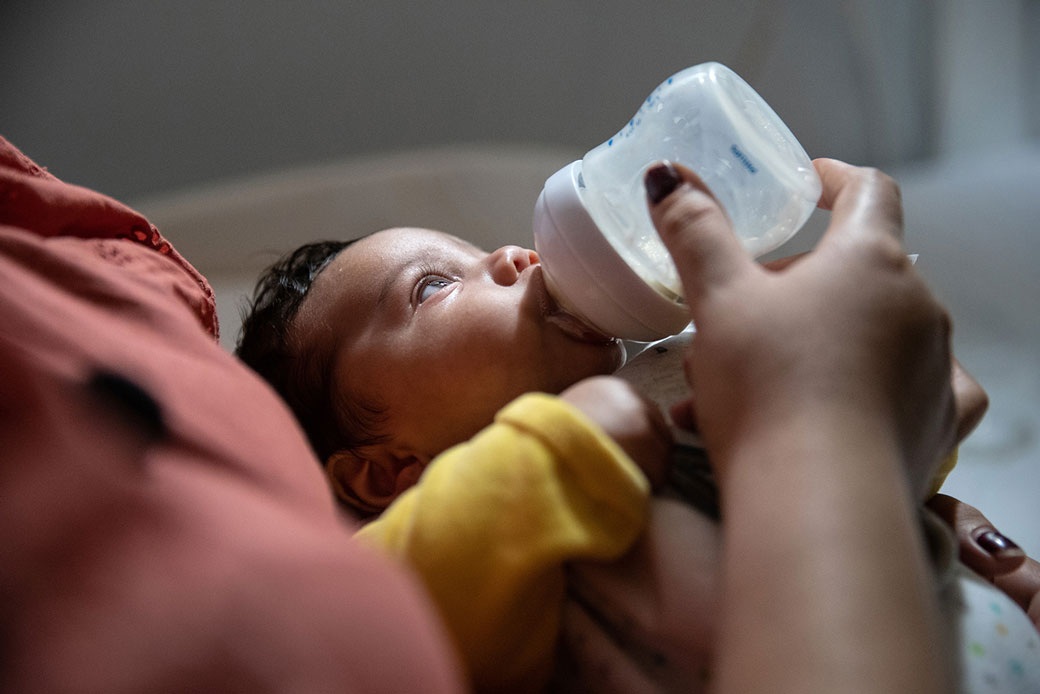 Toddler boy drinking milk from baby bottle stock photo - OFFSET