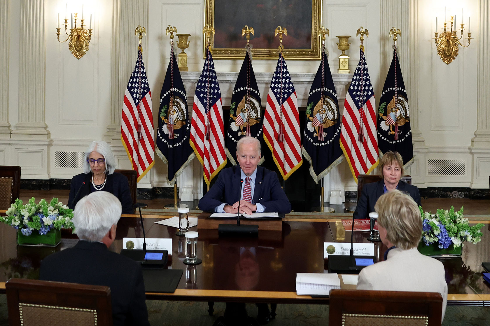 Image showing President Biden seated and surrounded by advisors.