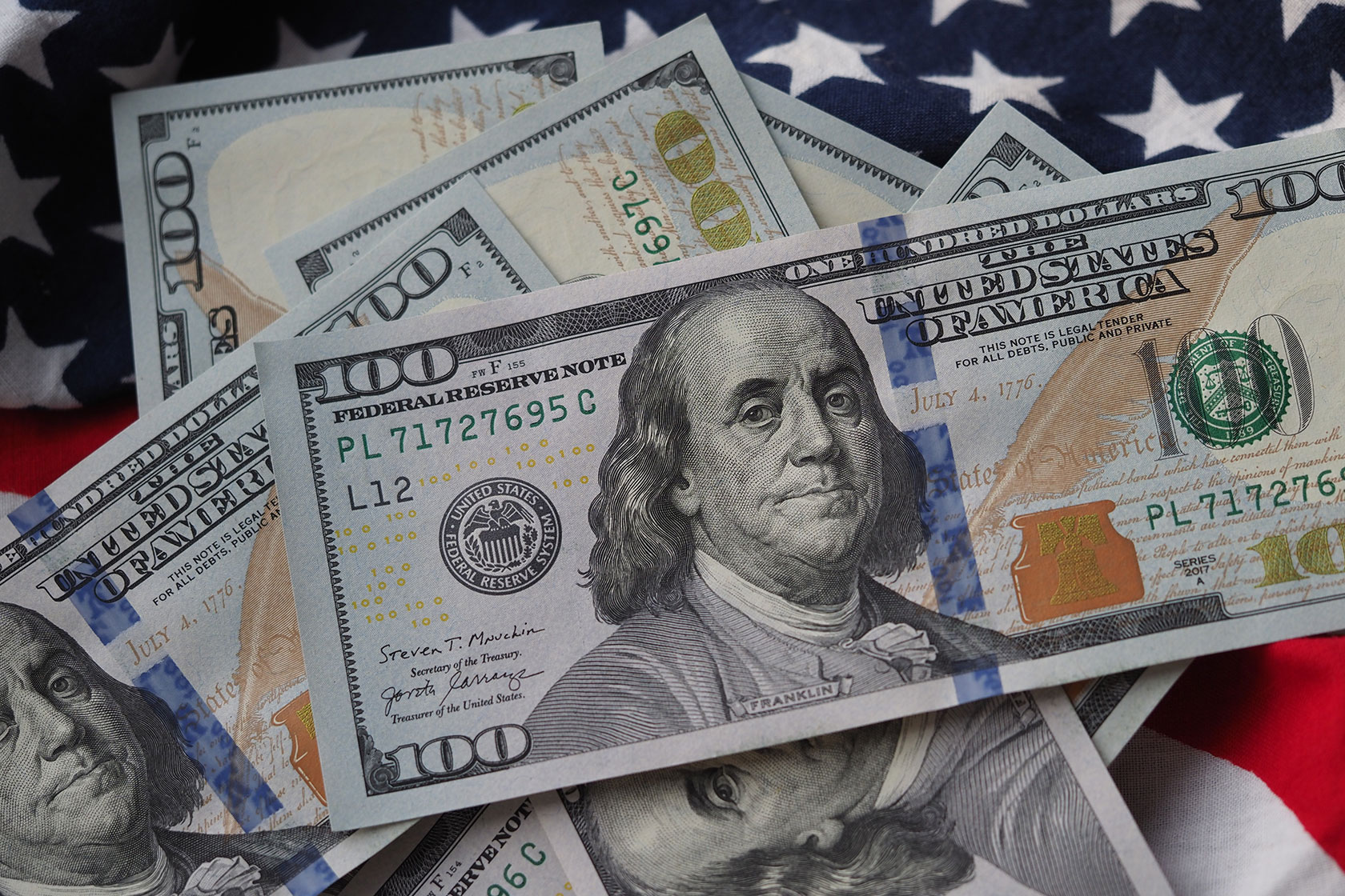 U.S. $100 bills are seen on an American flag.