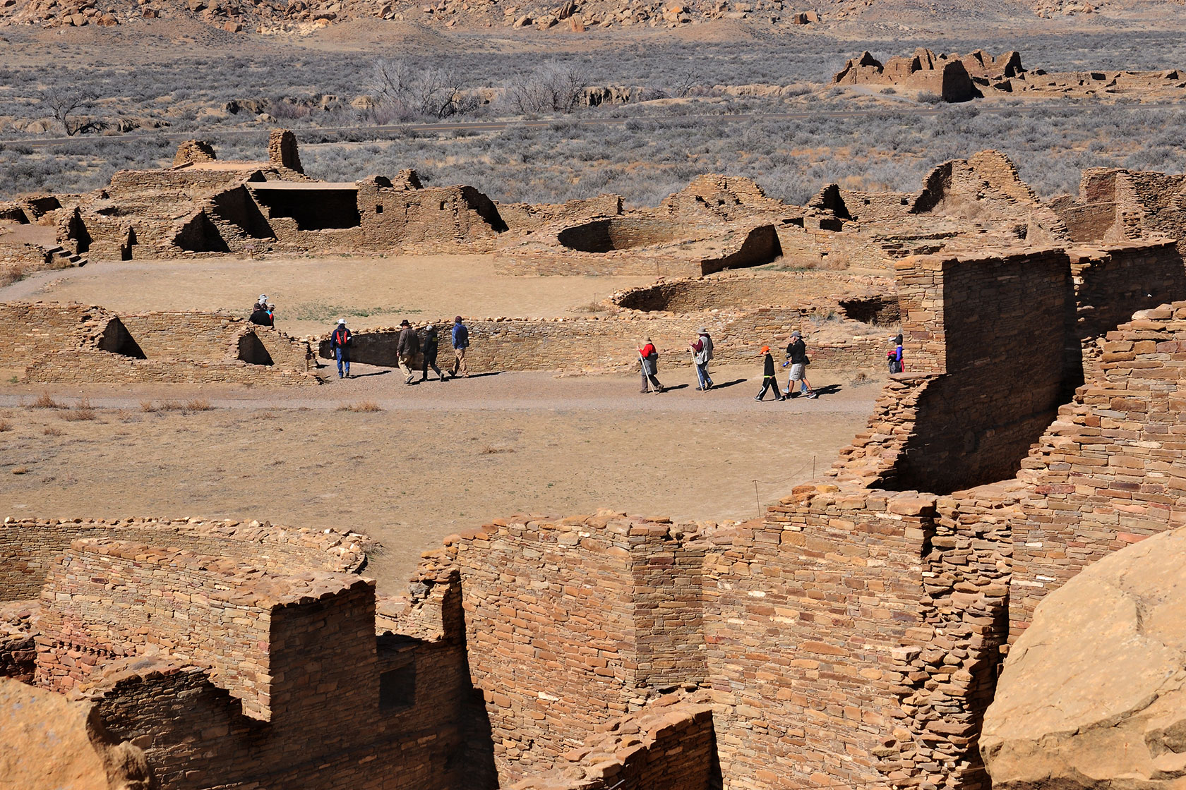 Visitors walk through the ruins of a massive stone complex at Chaco Culture National Historical Park.
