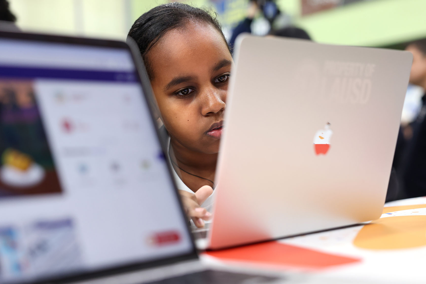 A young student is seen staring intently at a laptop screen.