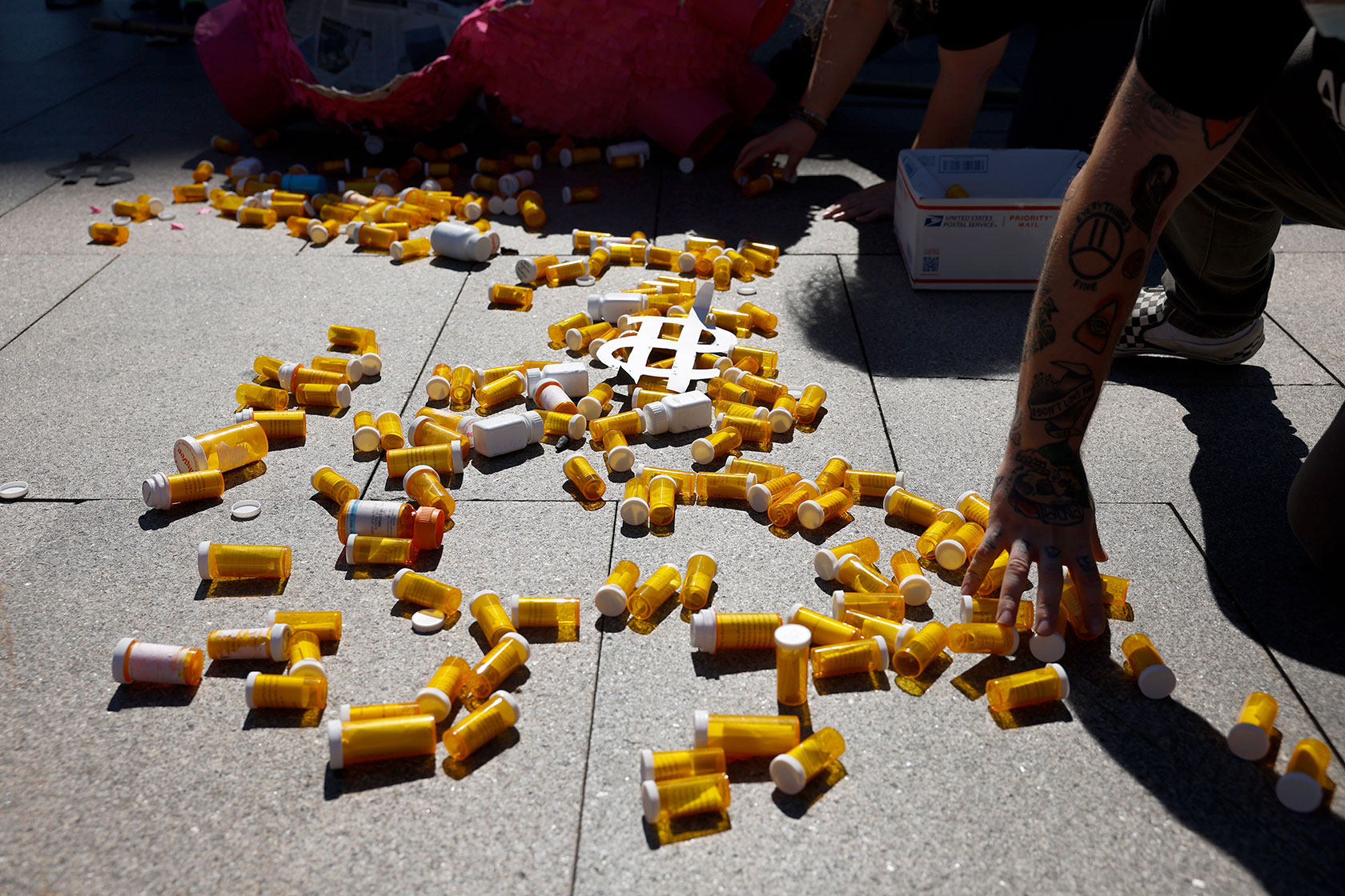 Empty pill bottles are scattered on the sidewalk during a protest.