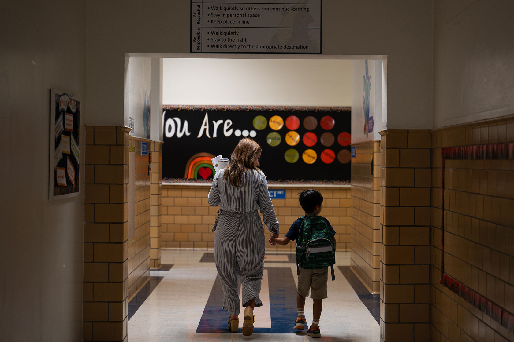 A teacher leads a student to their classroom.